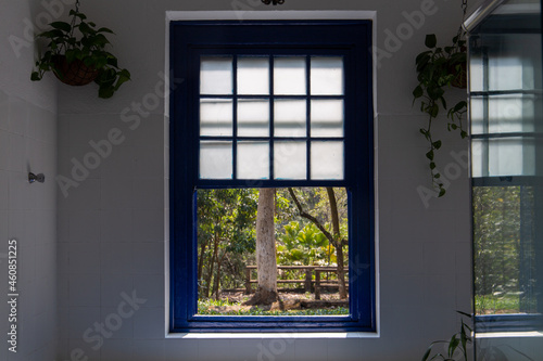 window overlooking nature on a farm in S  o Paulo  Brazil. Blue  old colonial windows. with white curtain