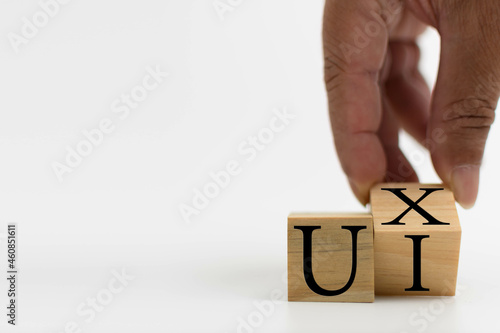 A wooden cube on a white table with text UI, UX. Concept of development and design and development, user interface, user experience, software, app. Copy space on left for a design, White background. © Mdisk