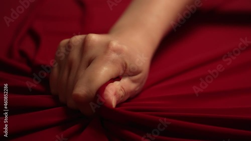 Woman hand passionately squeezes red bed sheet. Love concept. photo