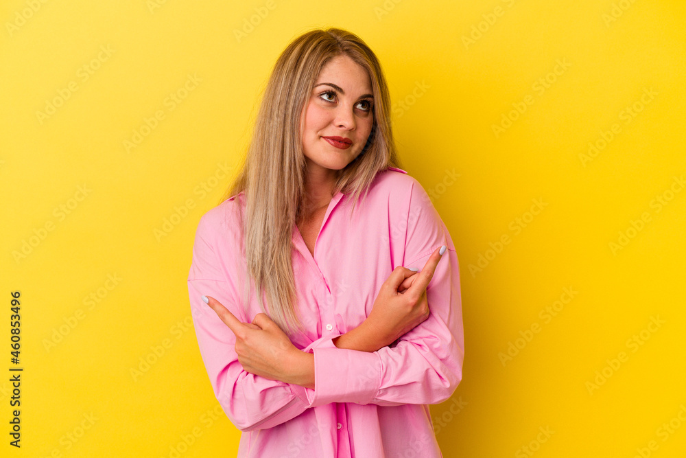 Young russian woman isolated on yellow background points sideways, is trying to choose between two options. Young russian woman isolated on yellow background points sideways, is trying to choose between two options.