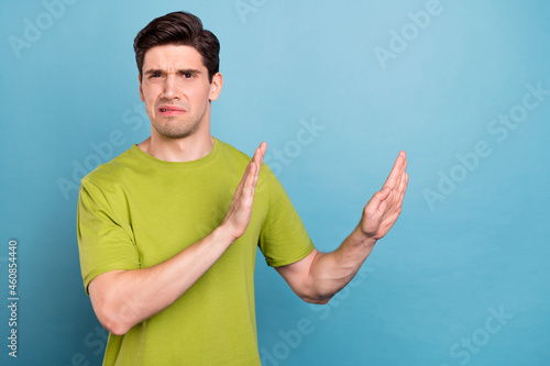 Photo of sad millennial brunet guy dislike wear green t-shirt isolated on blue color background