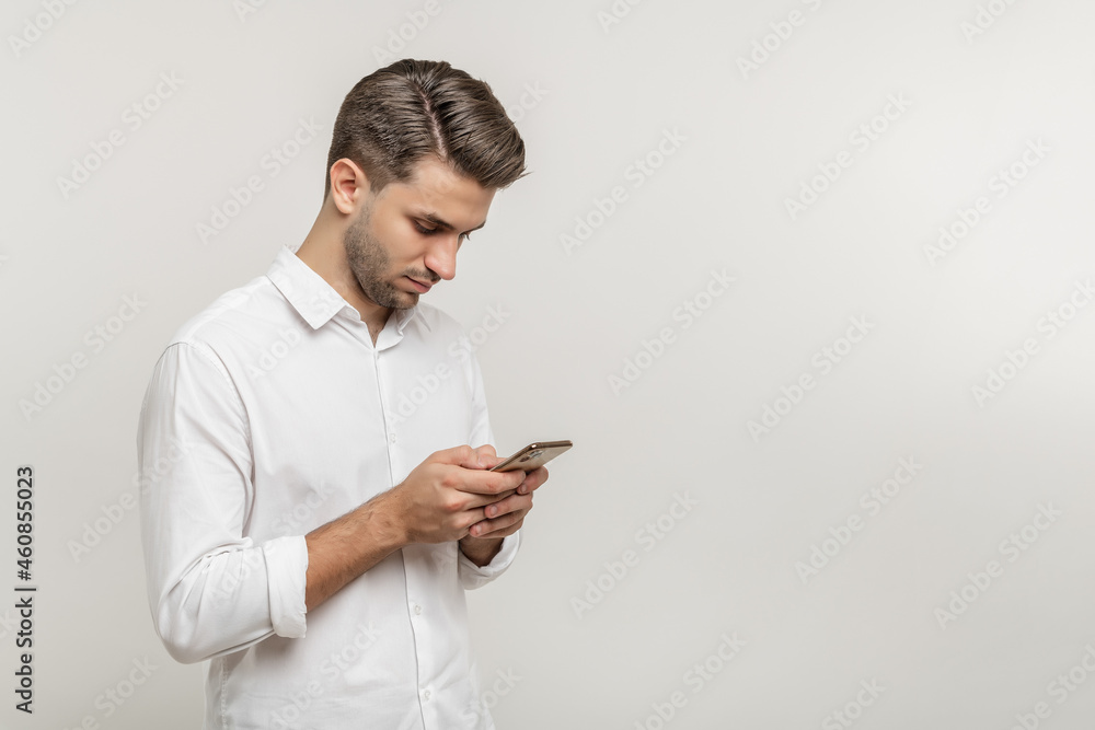 Profile portrait of handsome guy wearing white shirt sending and getting messages isolated against white background. Using phone concept. Profile portrait of handsome guy wearing white shirt sending and getting messages isolated against white background. Using phone concept.