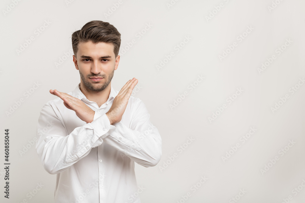 Portrait of attractive serious man showing stop sign crossed hands isolated over white background Portrait of attractive serious man showing stop sign crossed hands isolated over white background