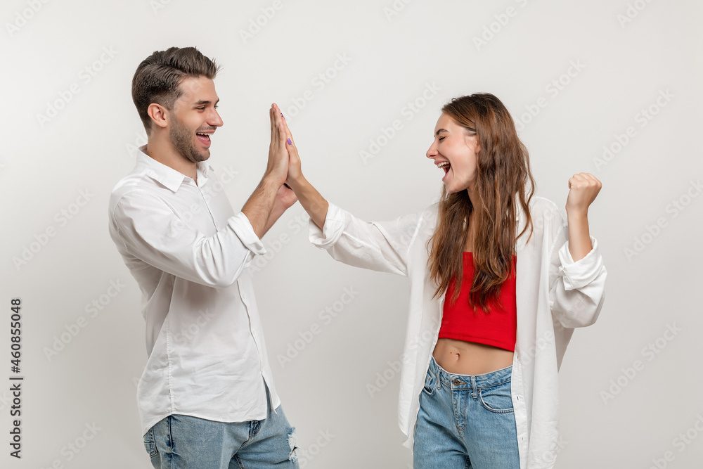 Portrait of joyful caucasian couple man and woman in casual clothes looking at each other giving high five isolated over white background Portrait of joyful caucasian couple man and woman in casual clothes looking at each other giving high five isolated over white background