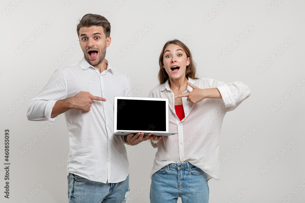 funny couple friends bearded guy girl in white shirts isolated on white background. People lifestyle concept. Mock up copy space. Pointing index fingers on laptop computer with empty screen funny couple friends bearded guy girl in white shirts isolated on white background. People lifestyle concept. Mock up copy space. Pointing index fingers on laptop computer with empty screen