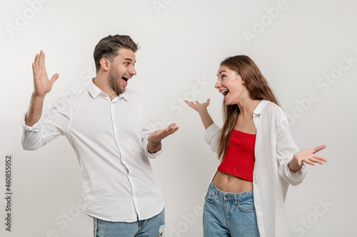 Surprised happy young couple looking at each other with open mouth isolated over white background, celebrating success photo