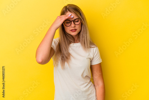 Young russian woman isolated on yellow background touching temples and having headache.