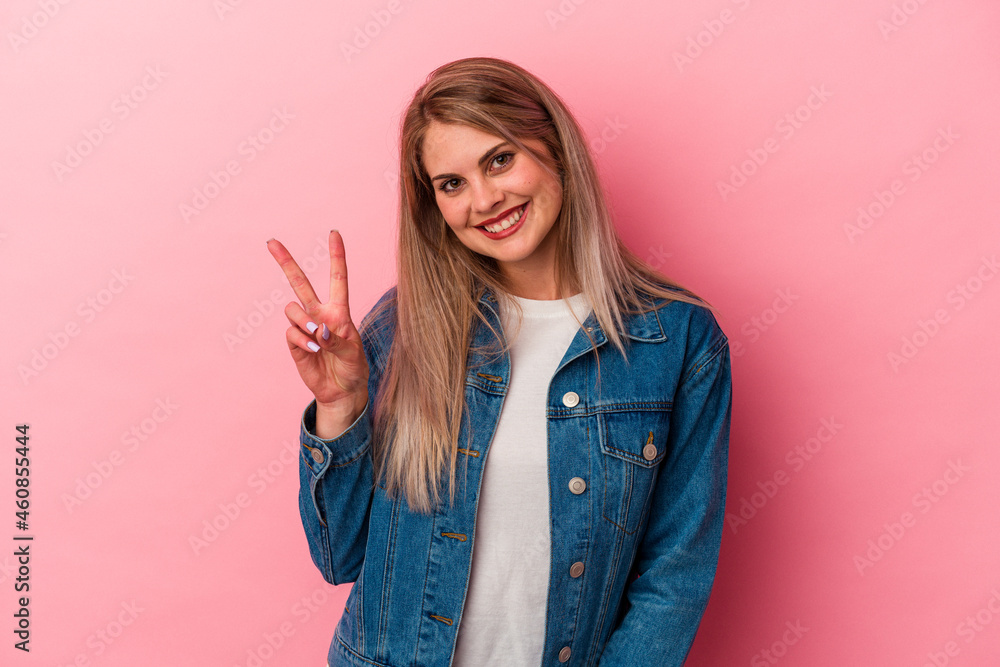 Young russian woman isolated on pink background showing victory sign and smiling broadly. Young russian woman isolated on pink background showing victory sign and smiling broadly.