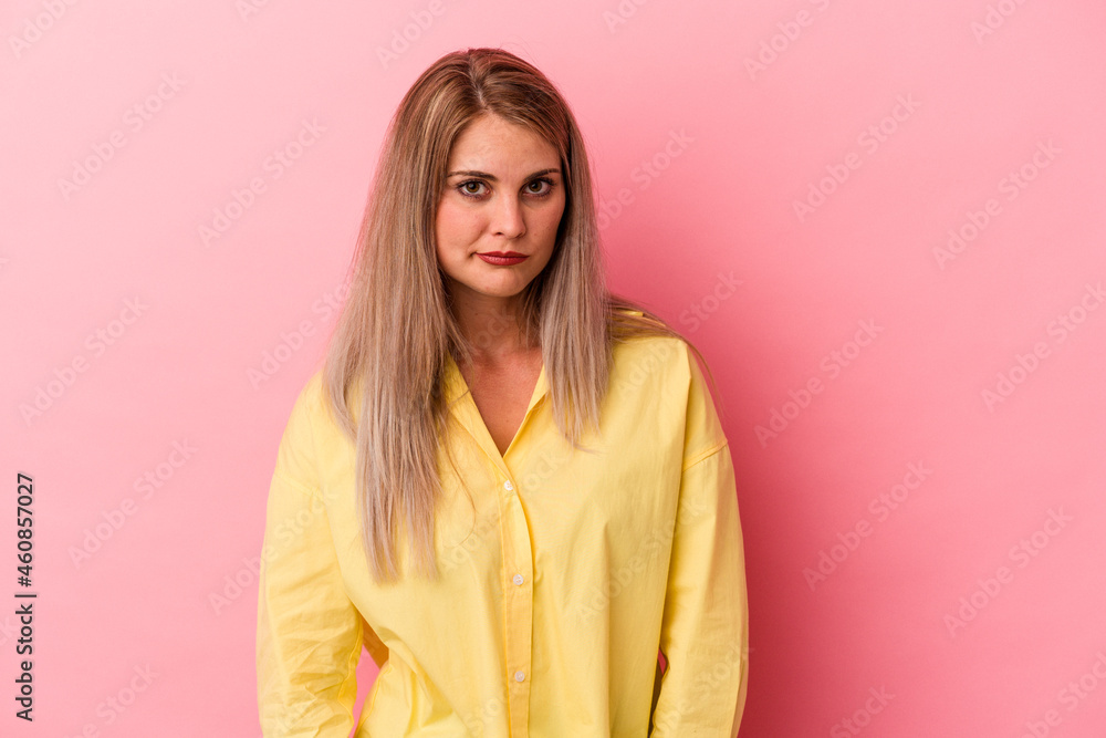 Young russian woman isolated on pink background sad, serious face, feeling miserable and displeased.