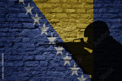 Soldier silhouette on the old brick wall with flag of bosnia and herzegovina country.