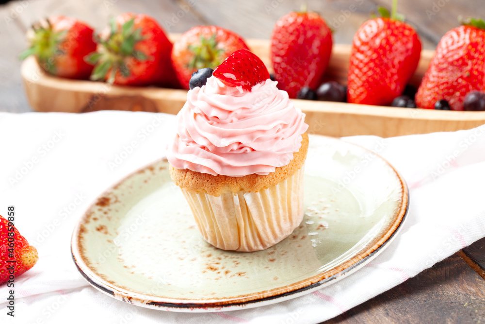 Strawberry muffin in a plate on a wooden table.
