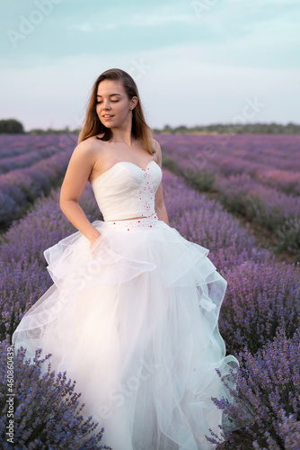 Portrait of the bride in a lavender field of flowers dressed in a white dress. Girl in the lavender bushes in summer. Happy wedding day in nature.