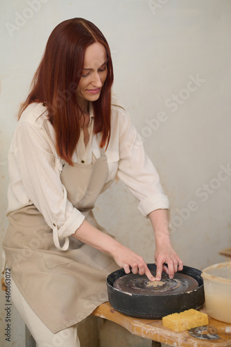 Female potter working on a pottery wheel in workshop