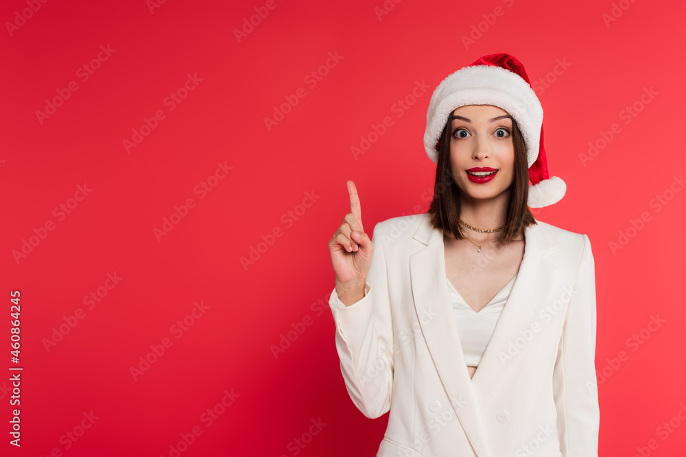Excited woman in santa hat having idea isolated on red Excited woman in santa hat having idea isolated on red