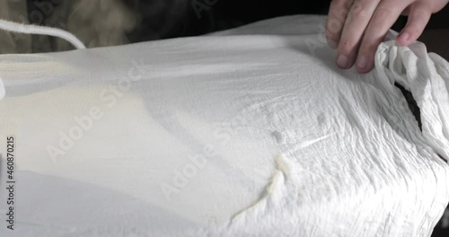 Male hands ironing clothes with iron on ironing board