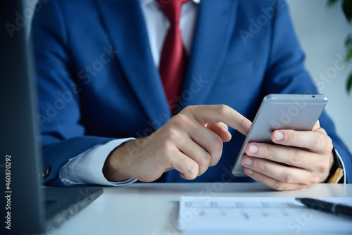 Businessman using smartphone in modern office.