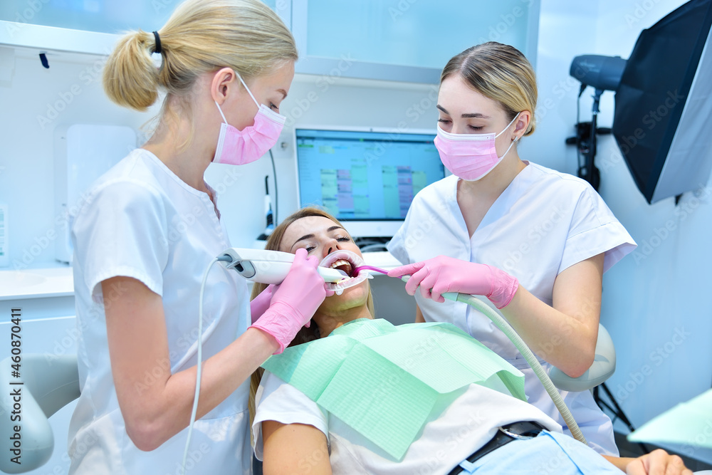 Orthodontist and assistant scaning patient's teeth with intraoral 3d scanner Orthodontist and assistant scaning patient's teeth with intraoral 3d scanner