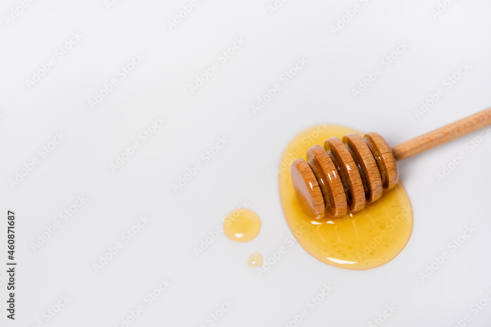 top view of wooden dipper near drops of honey on white background with copy space top view of wooden dipper near drops of honey on white background with copy space