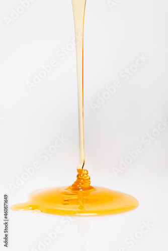 trickle of fresh golden honey flowing on white