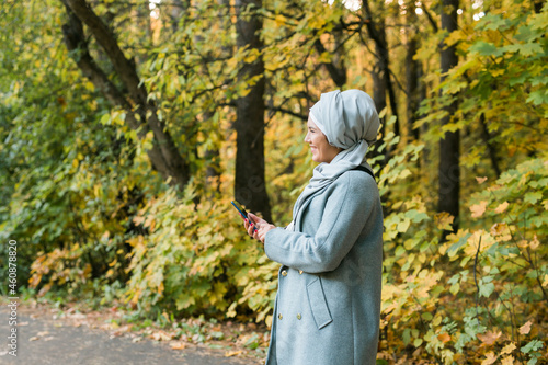 Muslim woman at the park using smartphone connected online wireless. Space for advertisement © satura_