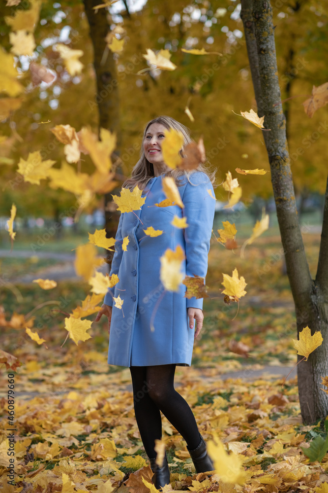 Young beautiful blonde girl in an autumn park in the maple leaves.
