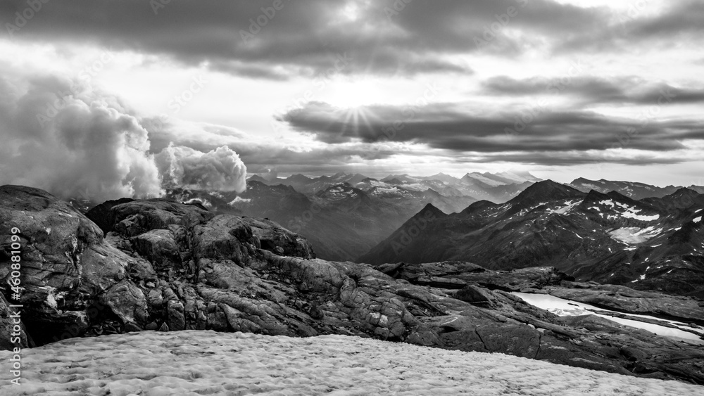 Rocky alpine mountains morning panorama. Cloudy sunrise on summer day. Grossglockner Mountain, Hohe Tauern National Park, Austrian Alps. Black and white image.