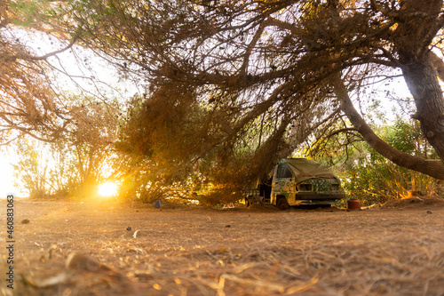Old camper van in the woods during sunset