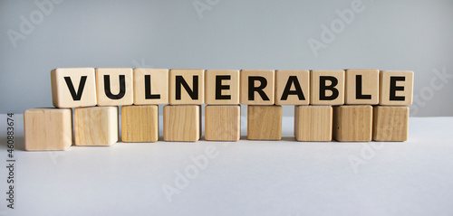 Vulnerable symbol. The word Vulnerable on wooden cubes. Beautiful white table, white background. Business and vulnerable concept. Copy space. photo