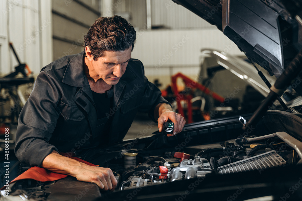 Waist up portrait image of senior mechanic in uniform is working in auto service. Car repair and maintenance concept Waist up portrait image of senior mechanic in uniform is working in auto service. Car repair and maintenance concept
