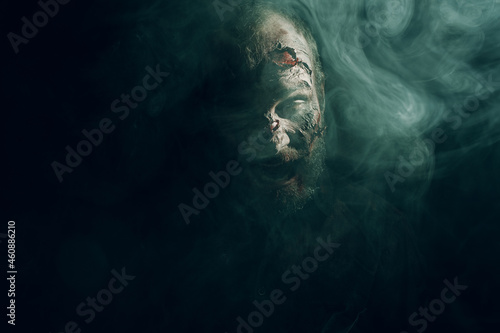 Zombie male in dark and smoke edge lit halloween concept. Make up skin and blood face