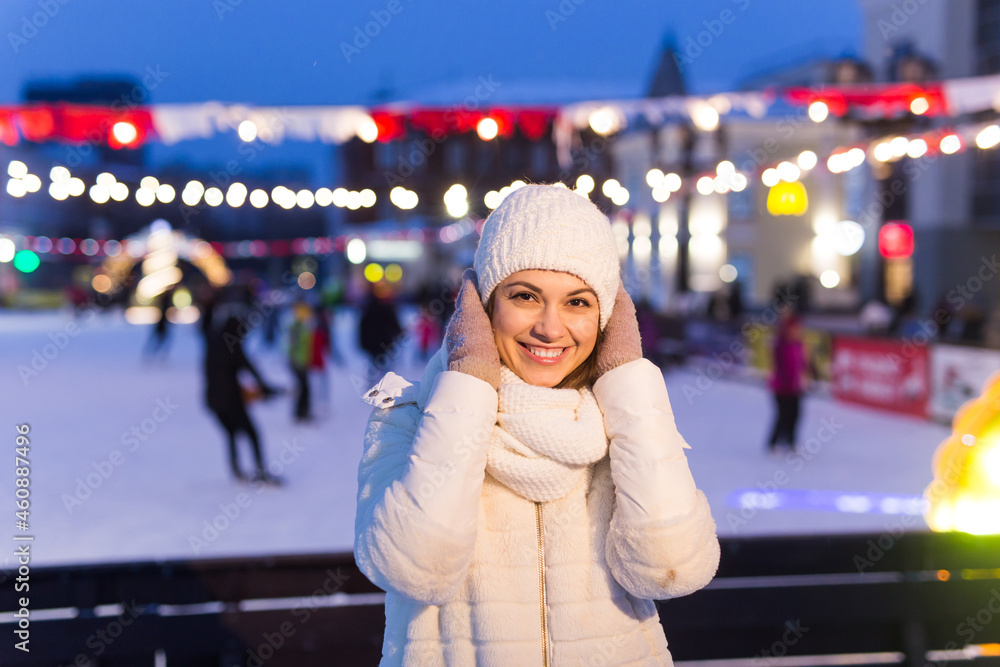 A woman near rink is skating. New Years Eve and Christmas. Fairy lights. Ice and snow mood concept. Winter sport. A woman near rink is skating. New Years Eve and Christmas. Fairy lights. Ice and snow mood concept. Winter sport.