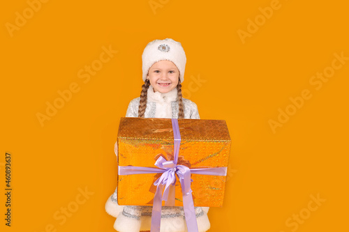 маленькая красивая девочка блондинка с косичками в национальном новогоднем костюме снегурочка держит в руках подарочную коробку