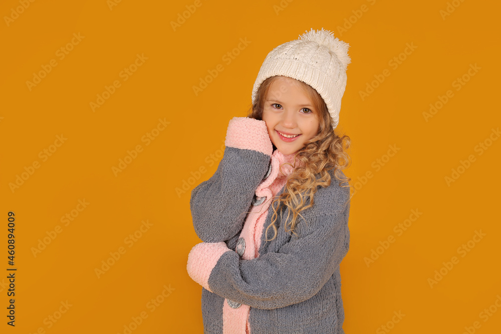 a little happy beautiful blonde girl in a white knitted hat and a knitted gray winter jacket a little happy beautiful blonde girl in a white knitted hat and a knitted gray winter jacket