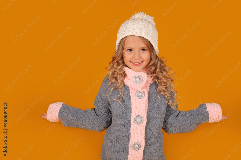 a little happy beautiful blonde girl in a white knitted hat and a knitted gray winter jacket a little happy beautiful blonde girl in a white knitted hat and a knitted gray winter jacket