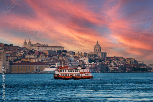 A traditional cacilheiro ferry boat crossing the Tagus River (Rio Tejo) with the city of Lisbon skyline on the background.