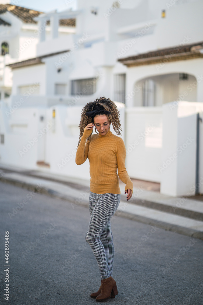 Chica delgada con pelo rizado posando en la calle