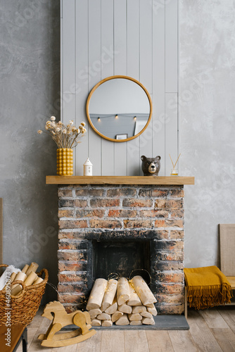 Scandinavian brick fireplace with wood and decor on it against the background of a gray wall of a country house