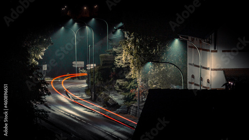 Cinematographic image of urban street at night with motion of red lights of a car passing by