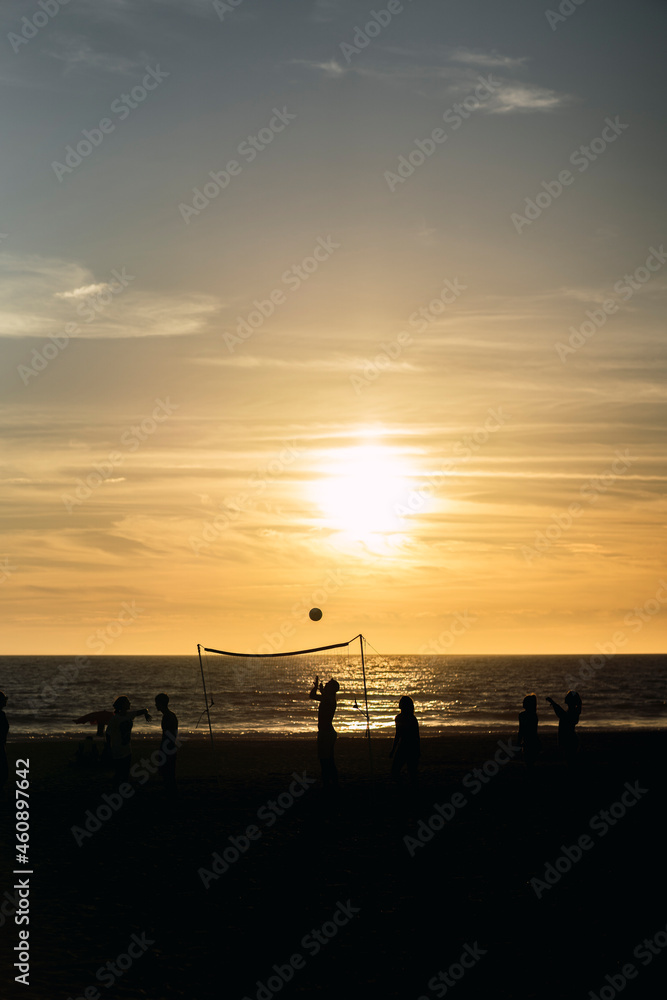 Siluetas de personas jugando en la playa al boleyball