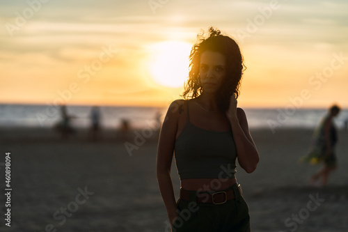 Chica delgada morena con aparatos en la playa al atardecer