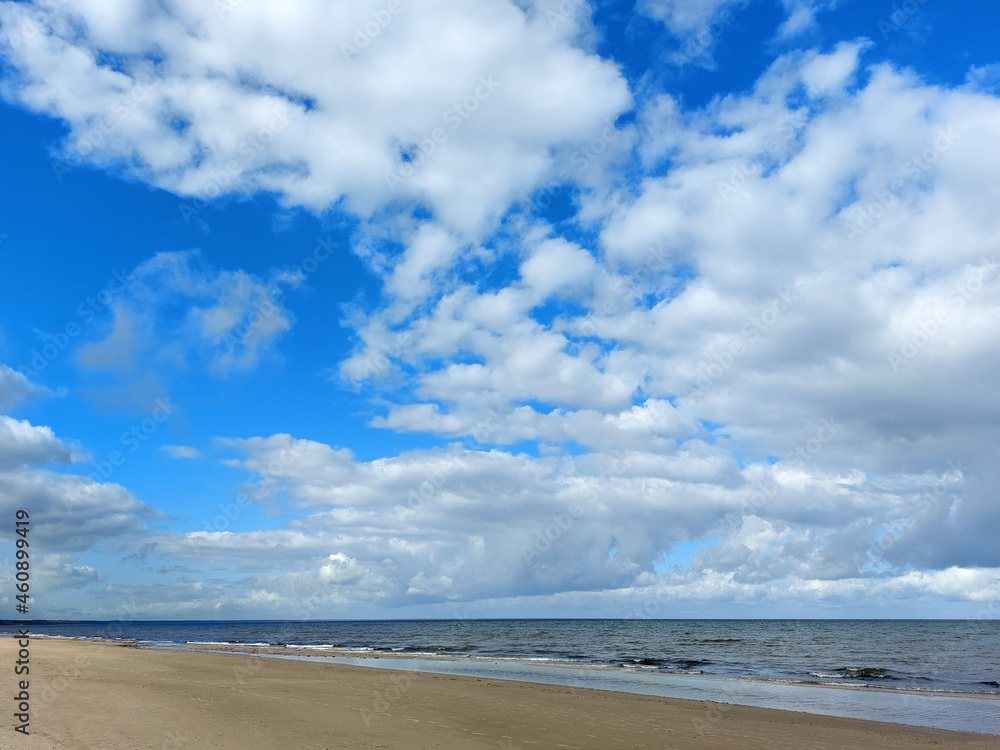 Gentle waves on the shore of the Baltic Sea and many white fluffy clouds on the sky