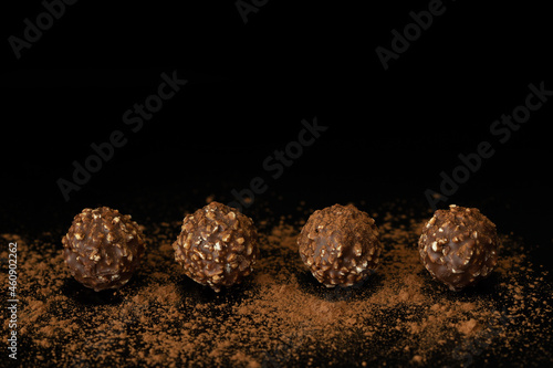 Chocolate ball candy with nuts on dark background with cocoa powder. Horizontal with copy space