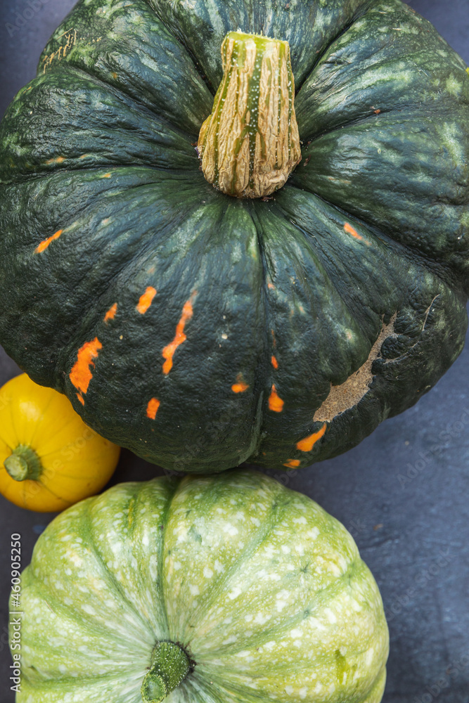 Autumnal Background. Natural autumn fall view pumpkins on dark black stone shale background. Change of seasons ripe organic food concept, Halloween party Thanksgiving day. Flat lay top view copy space Autumnal Background. Natural autumn fall view pumpkins on dark black stone shale background. Change of seasons ripe organic food concept, Halloween party Thanksgiving day. Flat lay top view copy space