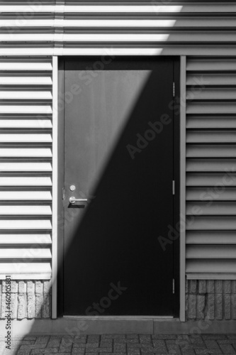 Sunlight and shadow on surface of black door of urban building