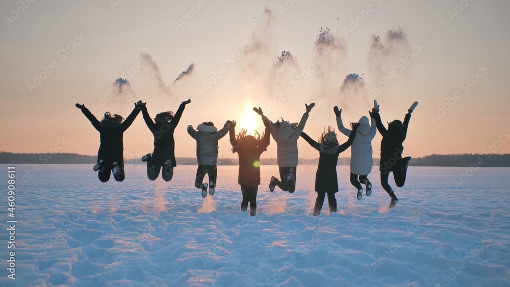Obraz premium A group of girls friends are throwing snow up at sunset.