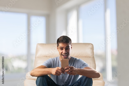 Cheerful Millennial Man Using Cellphone Browsing Internet And Texting