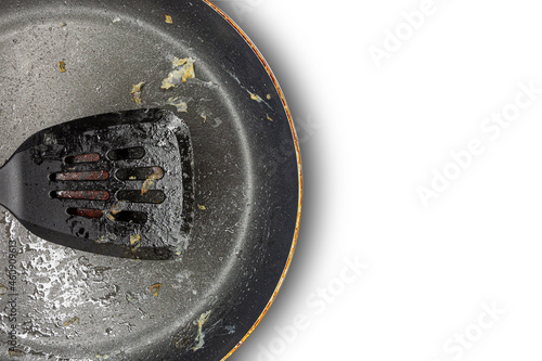 Fragment of a dirty frying pan and frying pan spatula on a white background. Copy space. Concept. photo