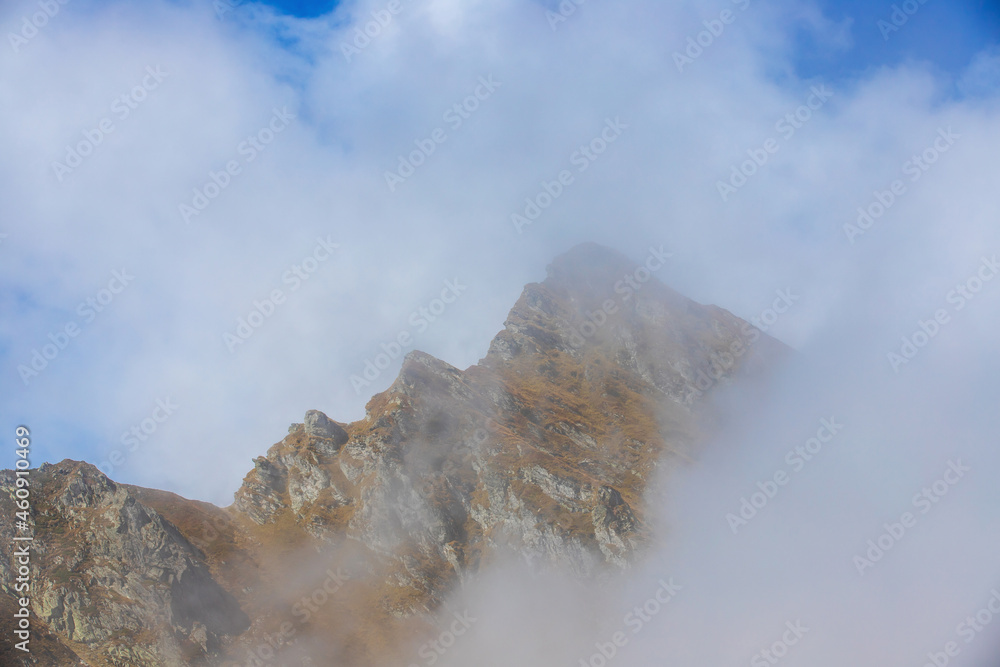 a mountain ridge emerging from the layer of clouds