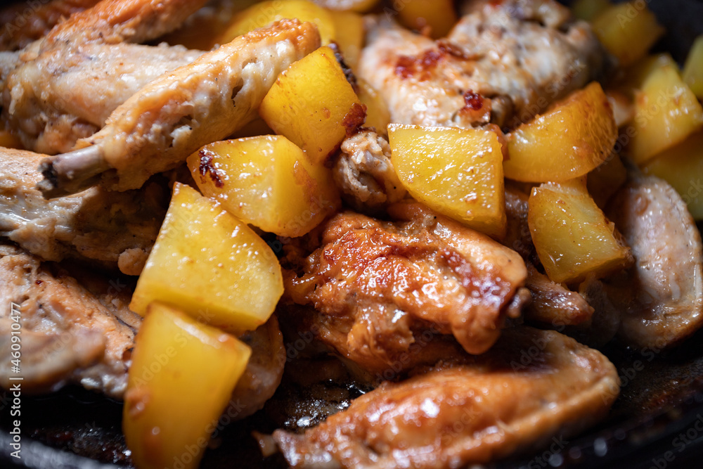 Fried chicken wings with potatoes are cooked in a pan, close-up with shallow depth of field Fried chicken wings with potatoes are cooked in a pan, close-up with shallow depth of field