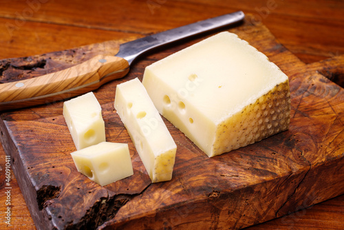Traditional Italian asiago milk cheese offered as close-up on a wooden board